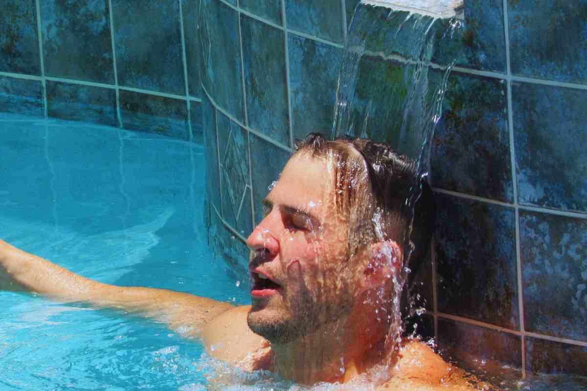 Uomo che cerca refrigerio sotto una cascata d'acqua