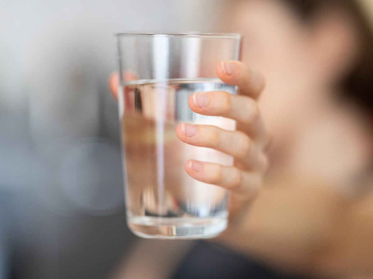 Persona tiene un bicchiere d'acqua in mano in primo piano