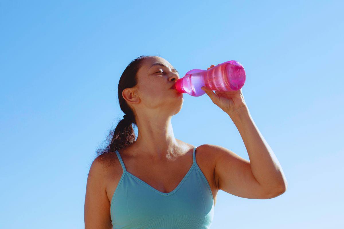 Donna che beve acqua da una borraccia