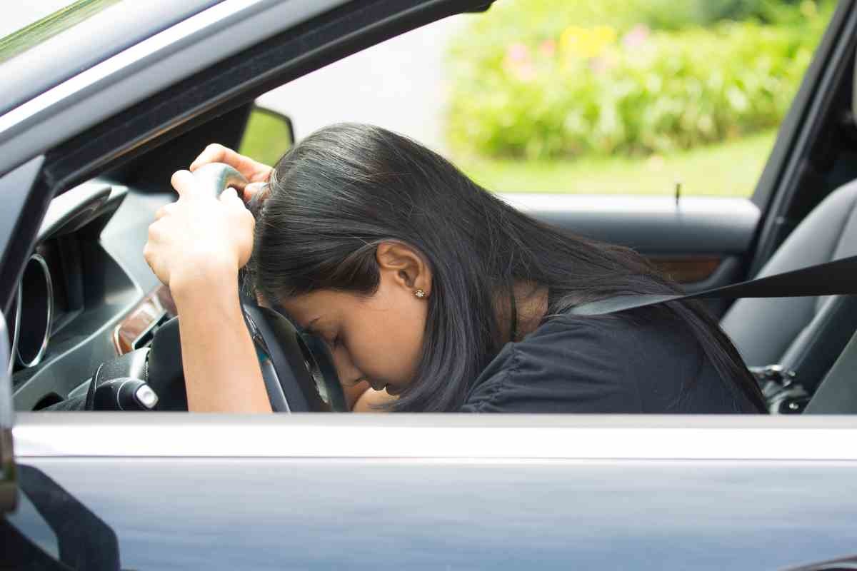 Donna poggiata sullo sterzo della sua auto