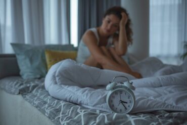donna che non dorme bene sul letto e sveglia