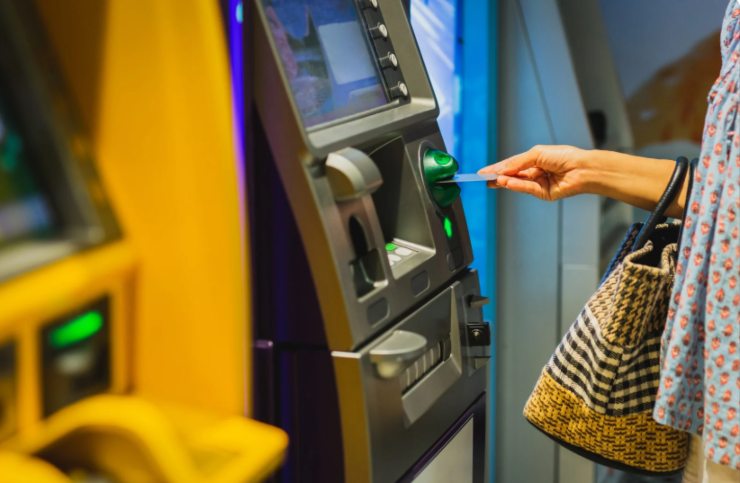 donna che inserisce il bancomat nella macchinetta per prelevare