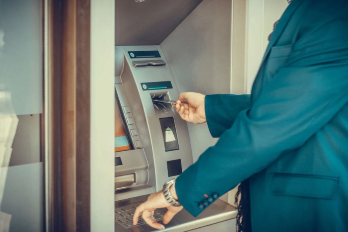 uomo che inserisce il bancomat nella macchinetta ATM