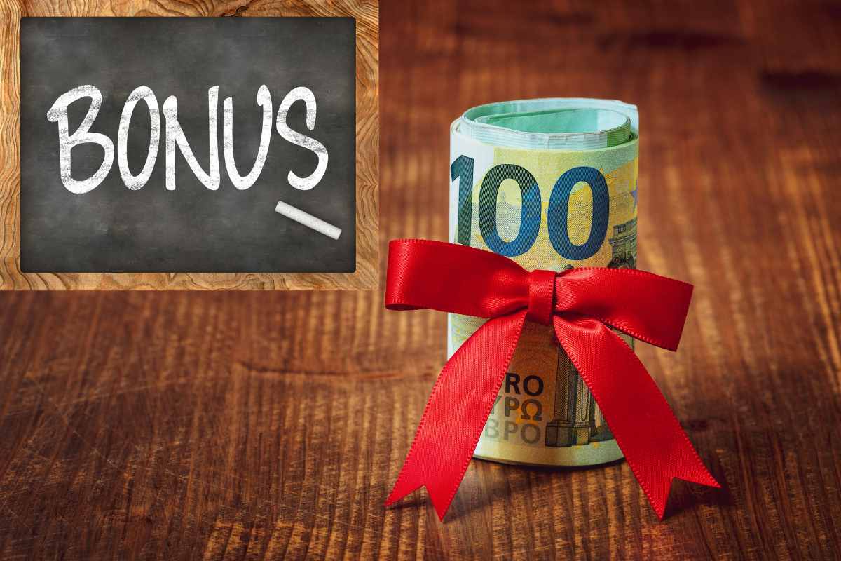 banconote 100 euro arrotolate con fiocco e lavagna con la scritta bonus