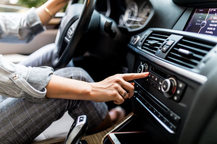 Donna al volante che regola l'aria condizionata