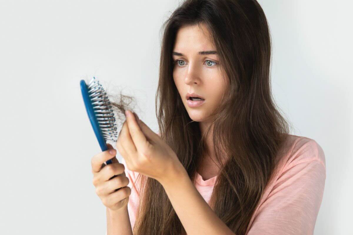 Ragazza stupita guarda capelli che ha perso attaccati alla spazzola