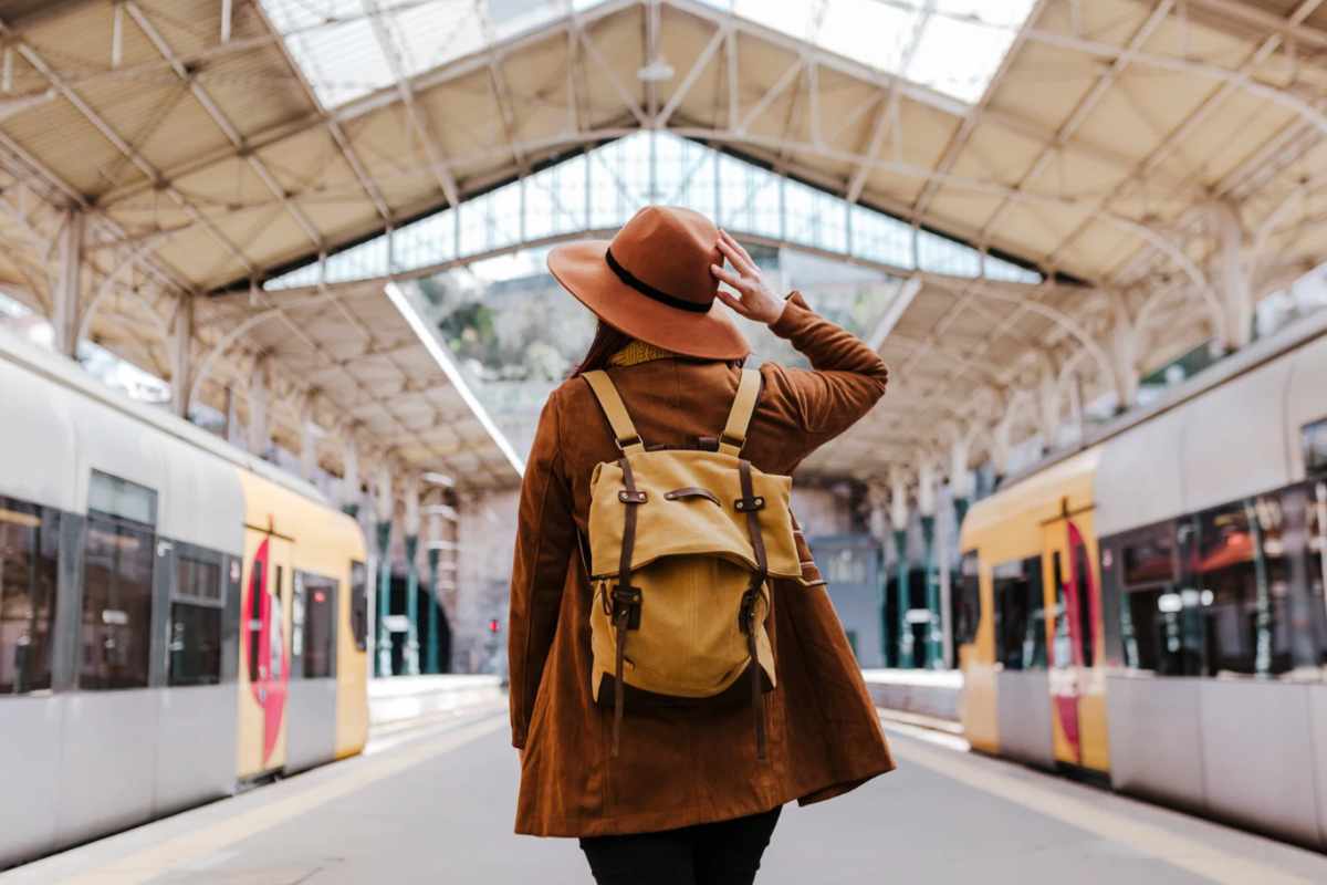 Donna con cappello e zaino alla stazione