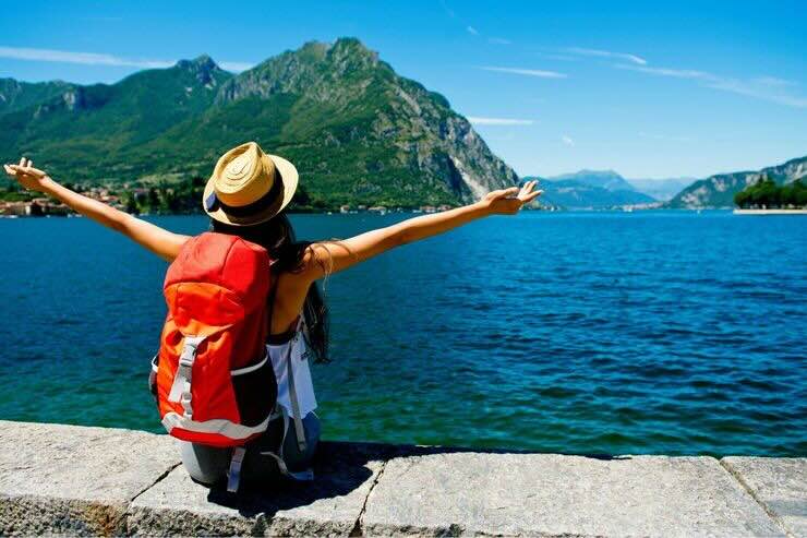 Donna di spalle con zaino su vista mare