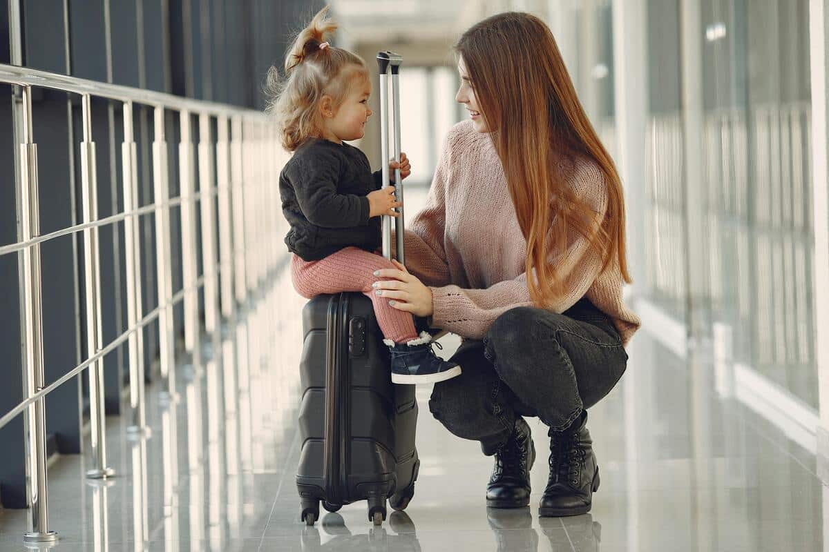 Mamma e figlia in aeroporto con la valigia