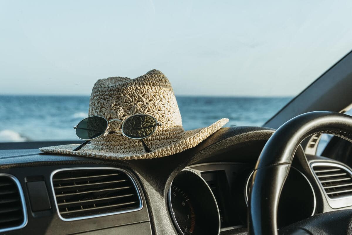 Cruscotto di un'auto con occhiali da sole e cappello di paglia