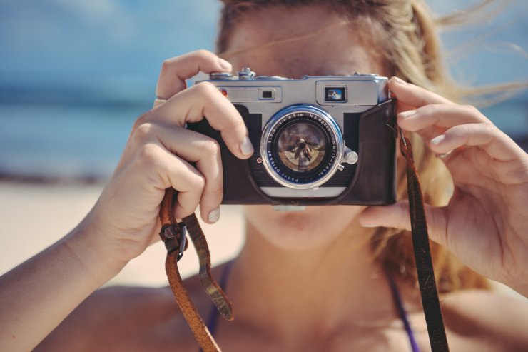 donna in spiaggia con macchina fotografica