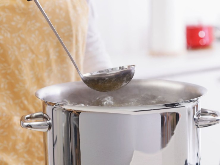 Persona che assaggia ciò che sta cucinando in una pentola