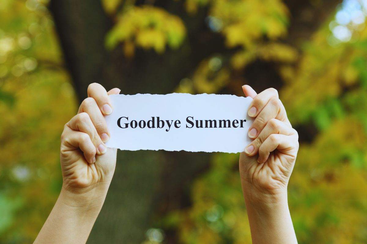 Donna che espone un cartoncino con su scritto "Googbye Summer"