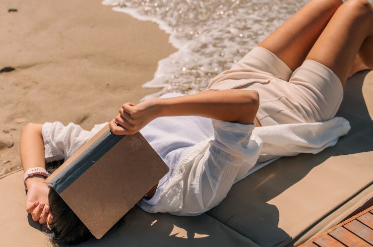 Ragazza sdraiata sul lettino con un libro sul volto