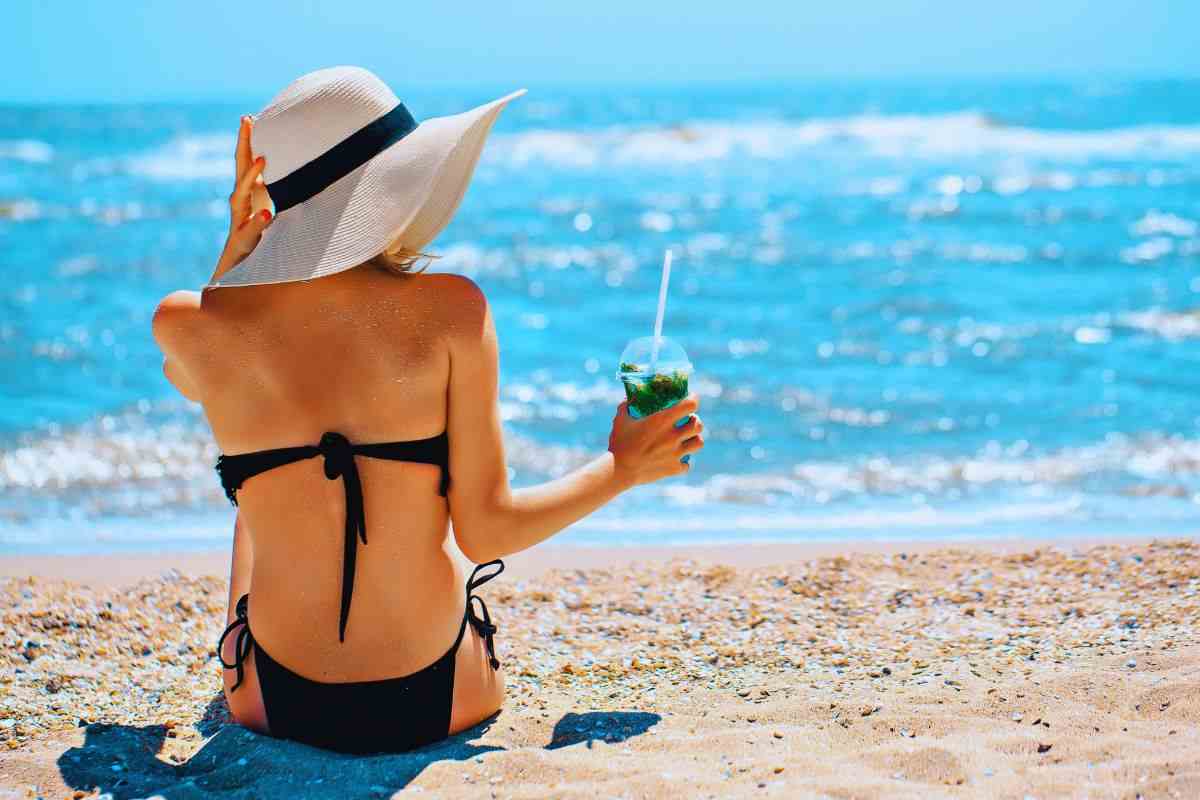 Donna che beve un cocktail in riva al mare