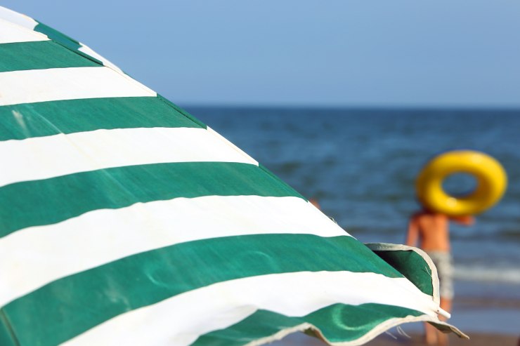 Ombrellone a righe verdi e bianche in primo piano e mare sullo sfondo