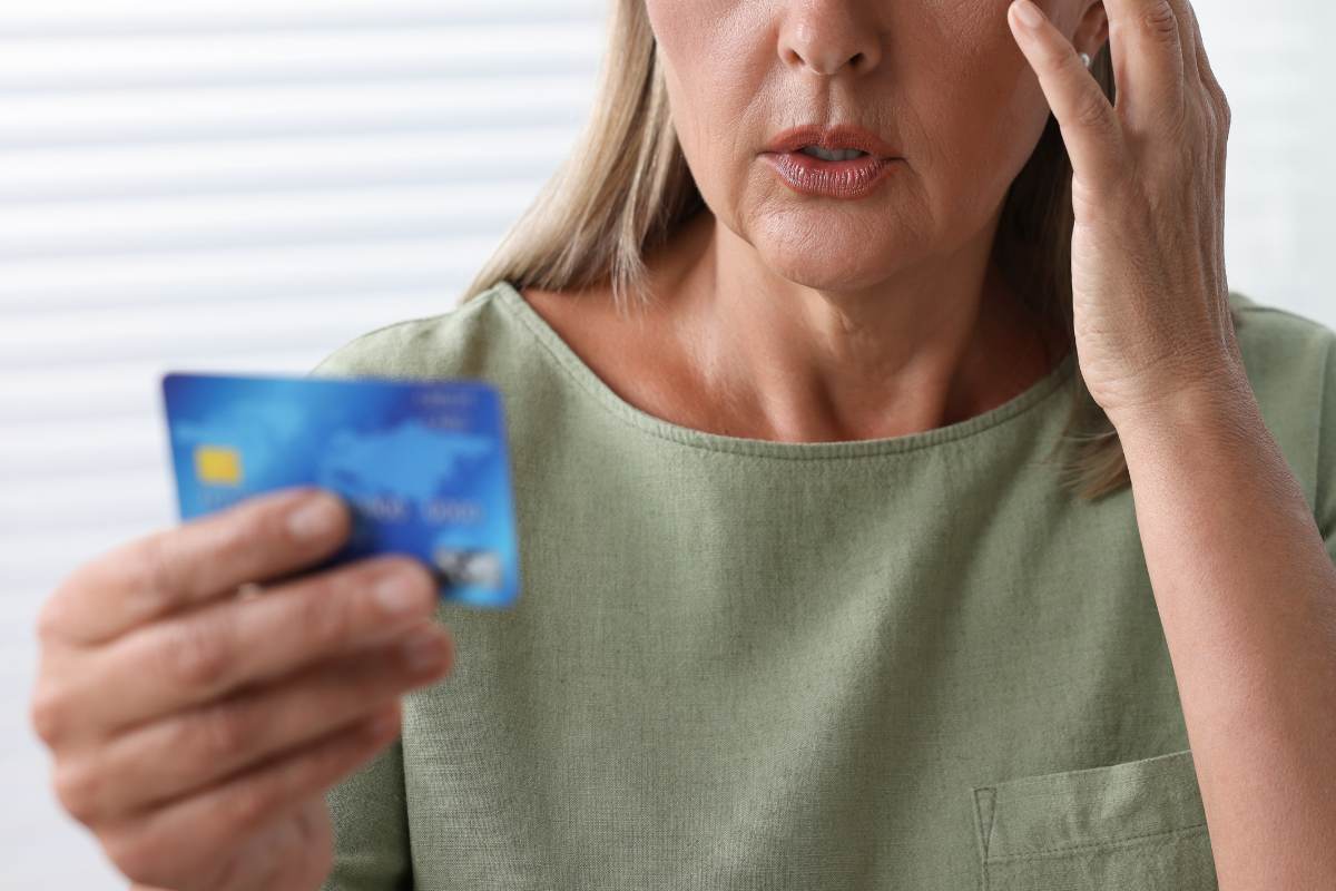 Primo piano donna con una carta di debito in mano, sconvolta dopo una truffa