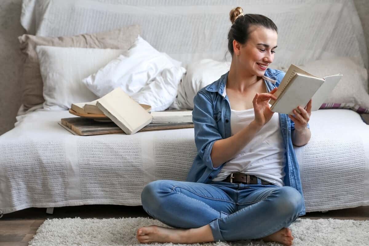 Ragazza seduta che legge di fianco a un letto