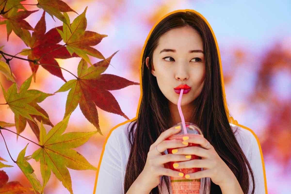 Donna che beve una bevanda e foglie autunnali
