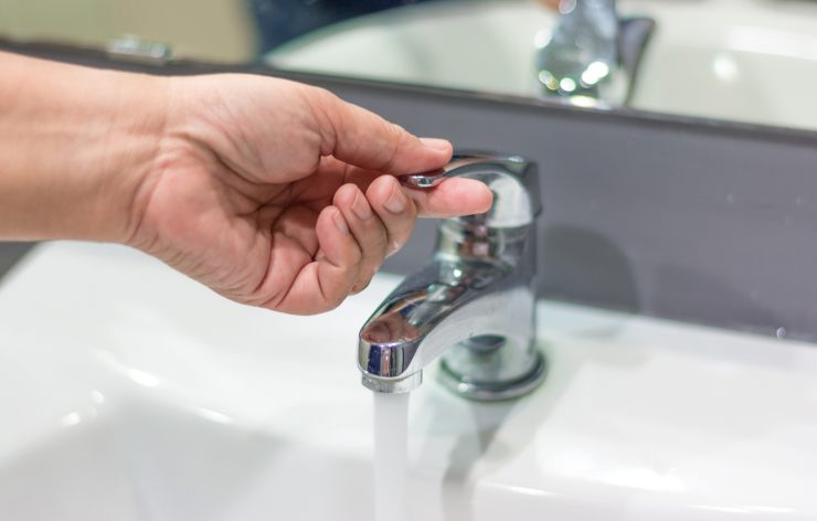 mano apre rubinetto acqua 