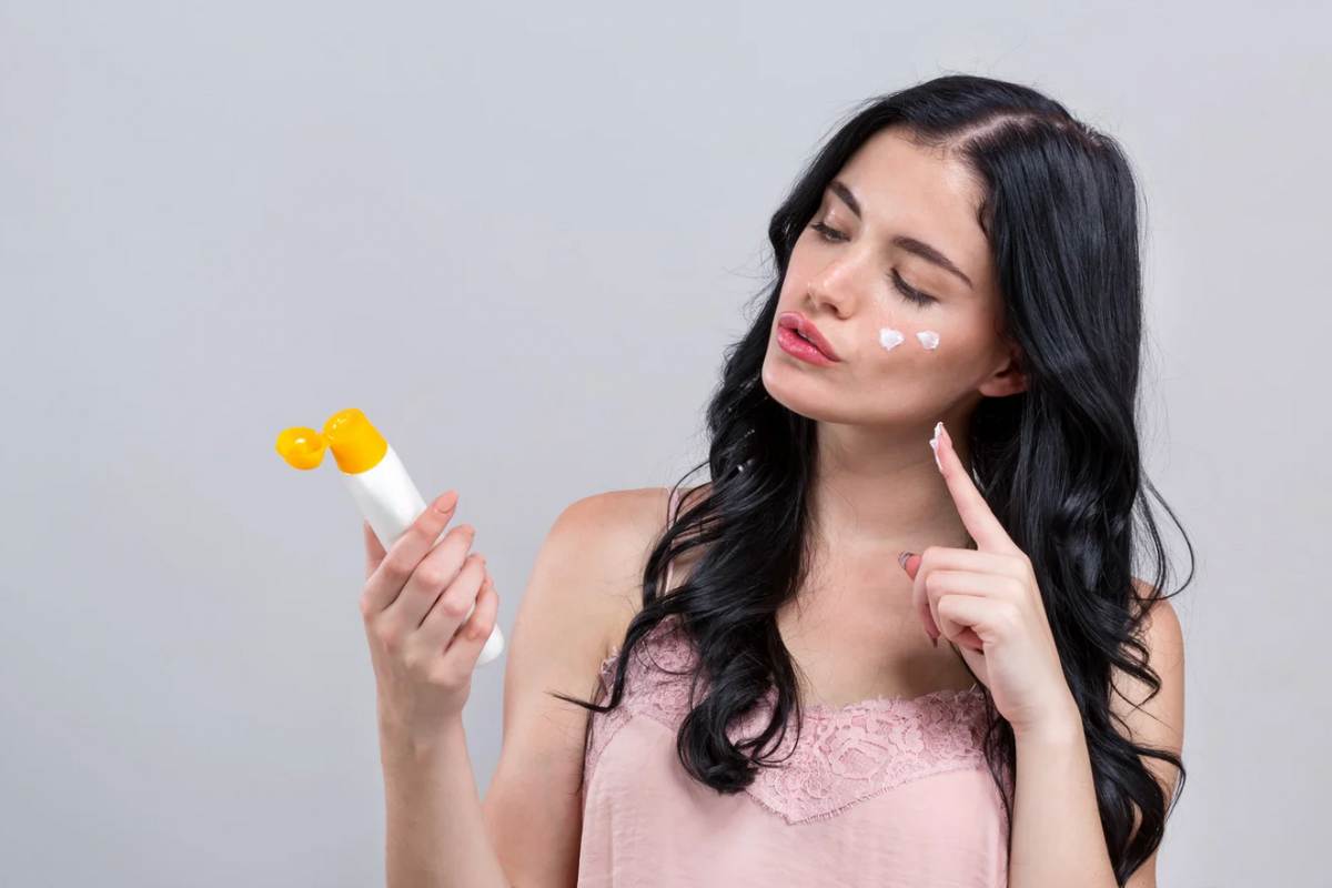 Donna che guarda flacone di crema solare