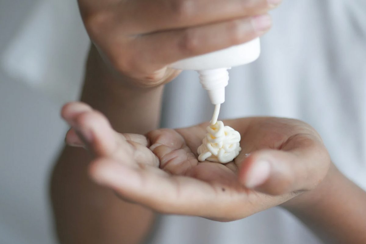 Persona che versa crema sulla mano