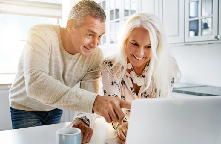 uomo e donna che sorridono mentre guardano il computer
