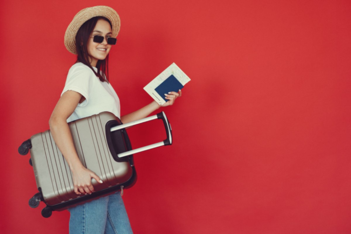 donna con in mano il passaporto che solleva una valigia
