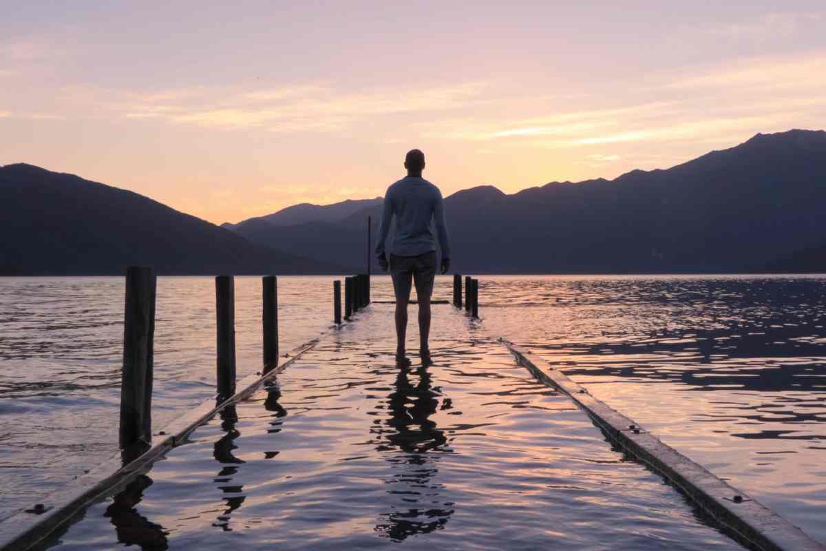 Un uomo su un pontile di un lago al tramonto