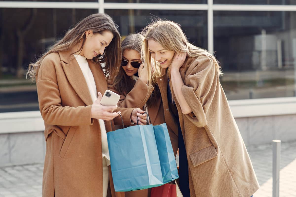 Ragazze con borse da shopping che guardano il telefono