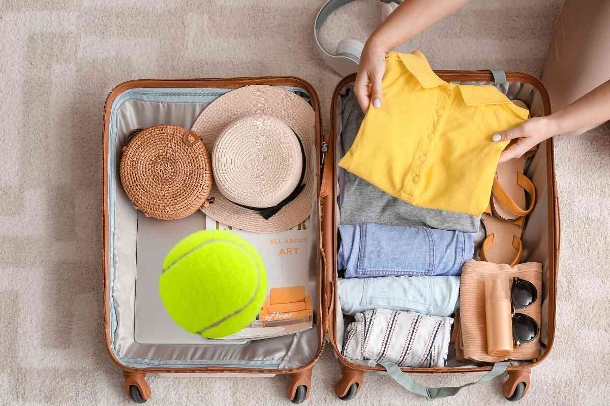 pallina da tennis insieme a vestiti in valigia