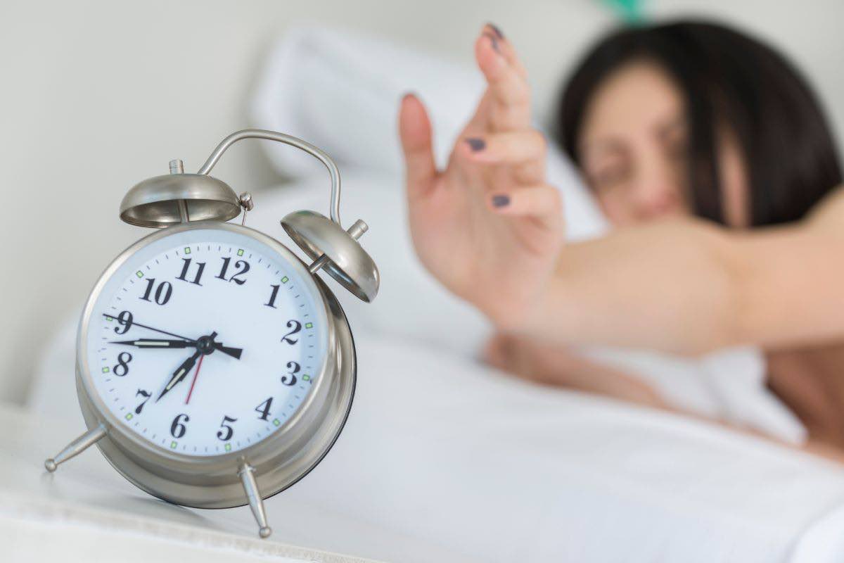 Persona a letto con sveglia accanto
