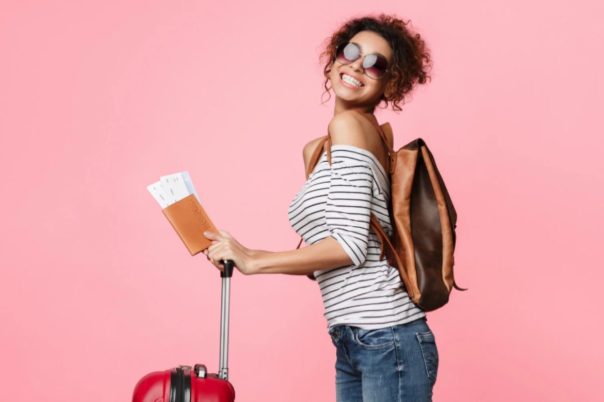 donna sorridente con la valigia e il passaporto