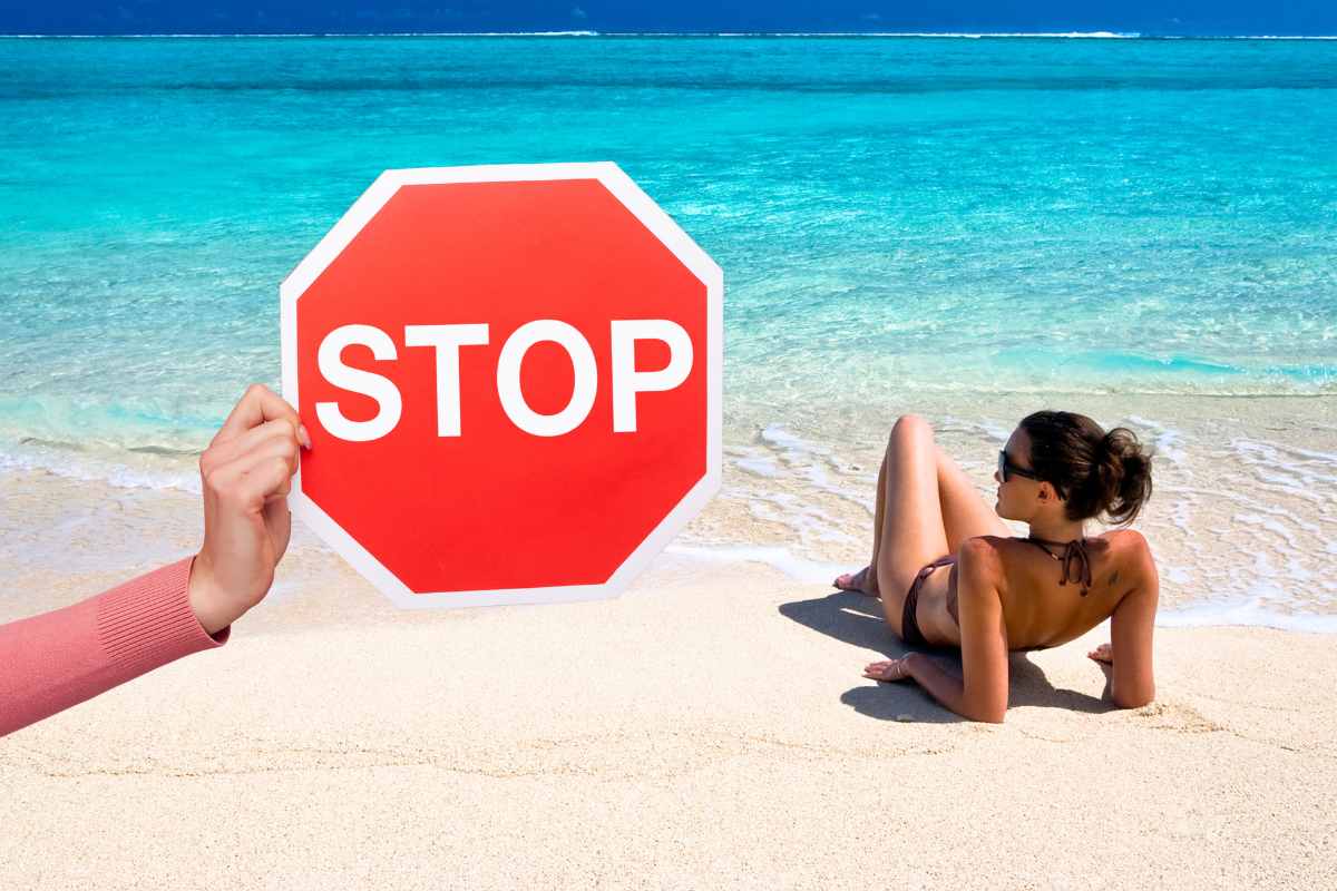 segnale stop e donna stesa su spiaggia mare