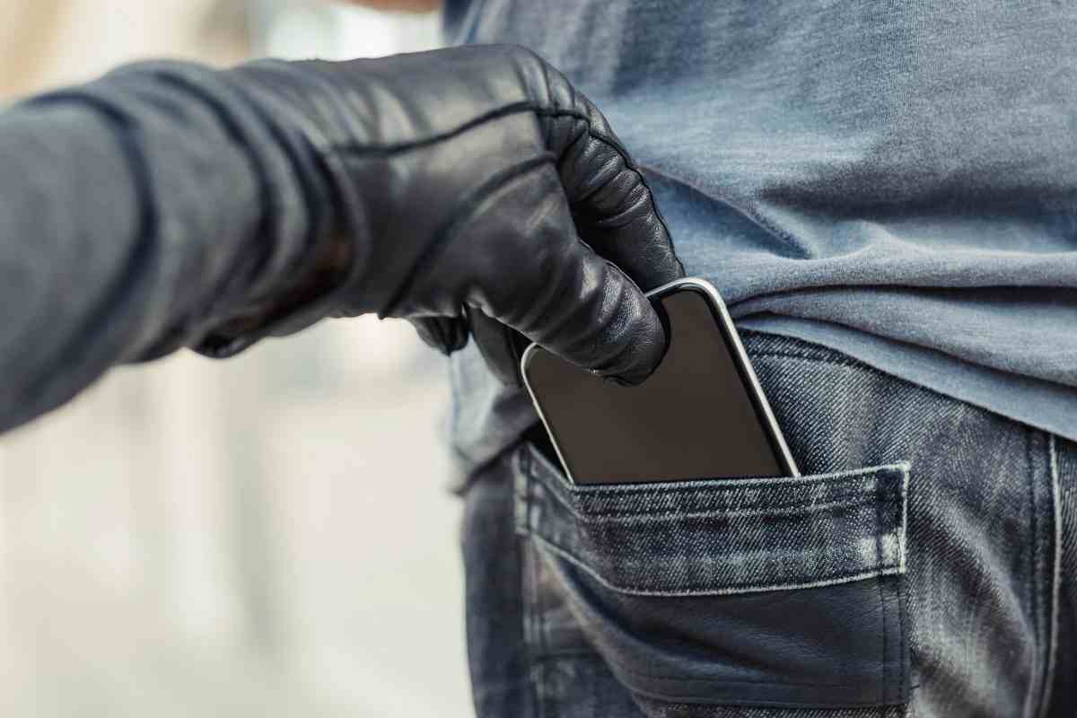 Persona che sfila cellulare dalla tasca dei pantaloni di un altro