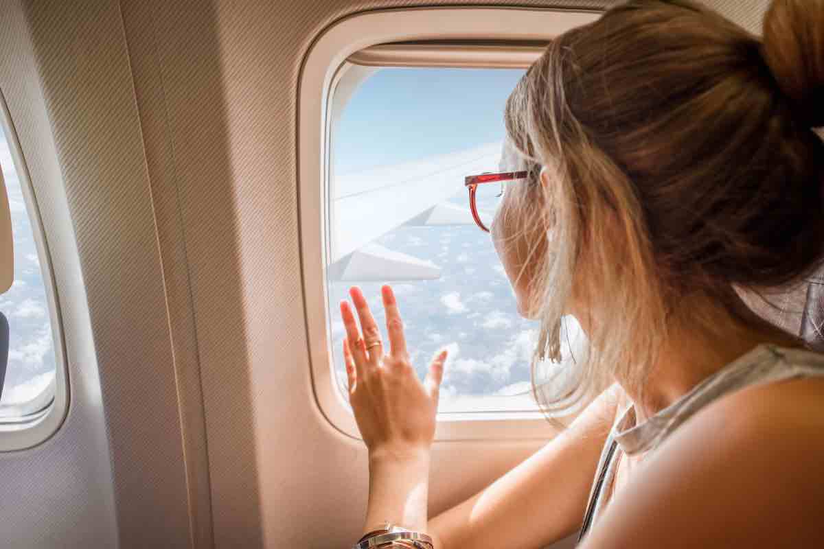 Donna che guarda fuori finestrino aereo