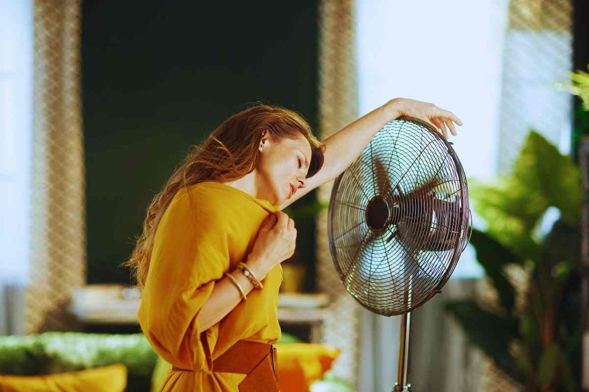 Donna accaldata che cerca refrigerio davanti al ventilatore