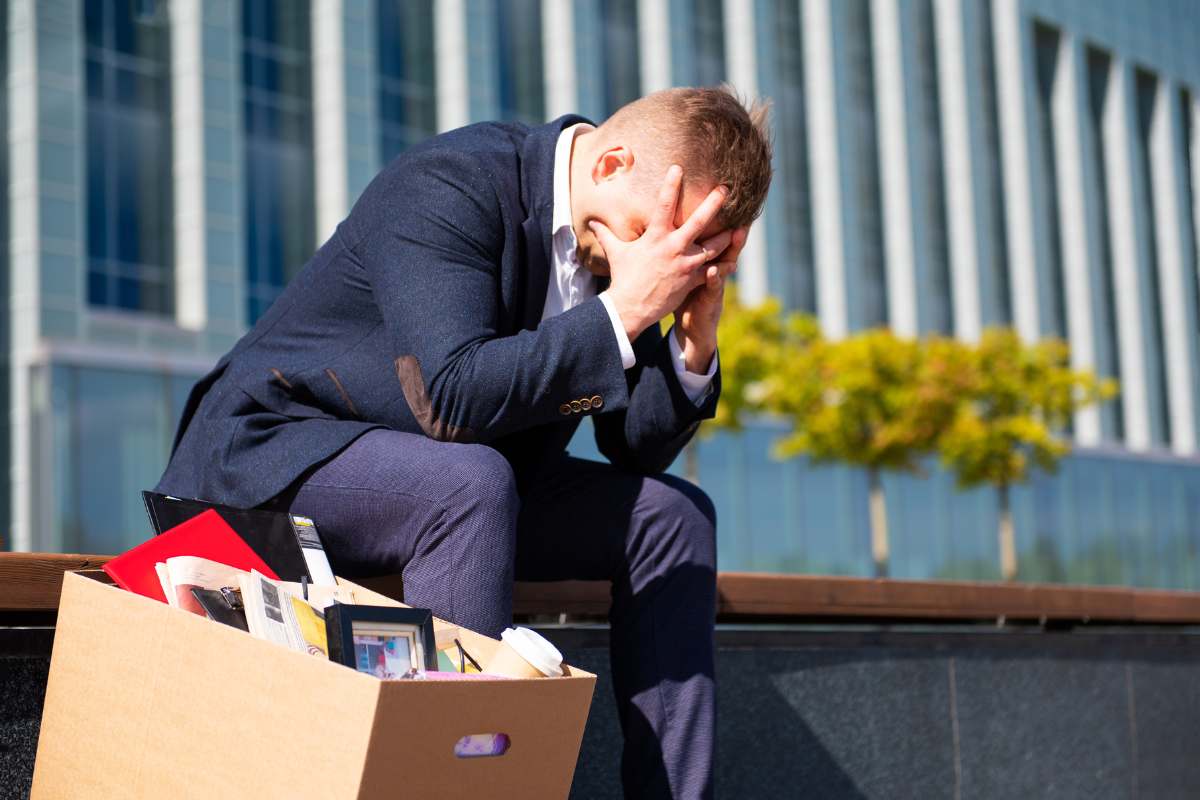 Dipendente disperato seduto sulle scale fuori dall'ufficio dopo il suo licenziamento