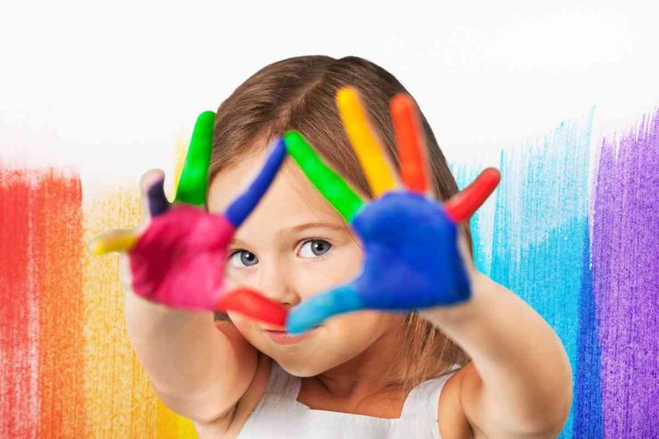 Bambina con mani colorate 