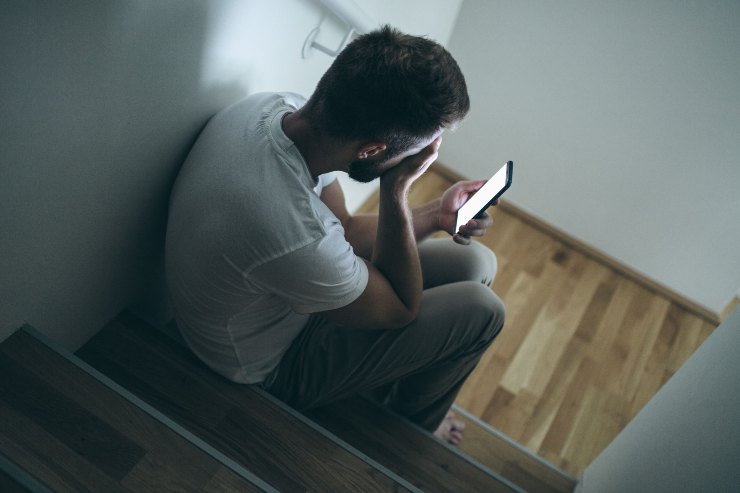 Uomo con postura depressa mentre guarda lo smartphone