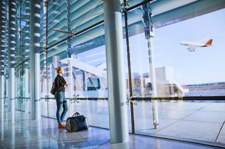 Ragazza che osserva aereo dall'interno di un aeroporto