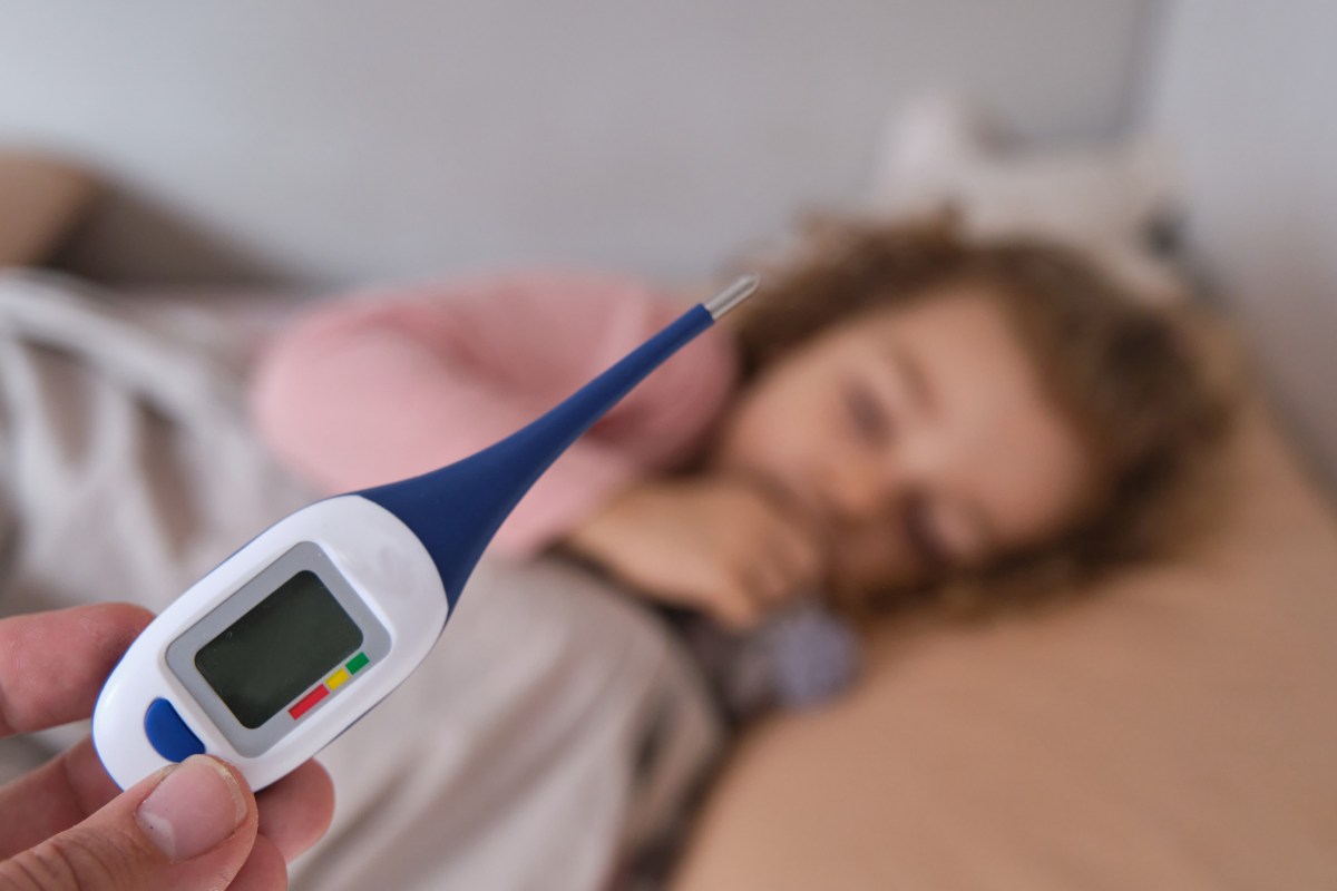 termometro digitale e in secondo piano bambino a letto