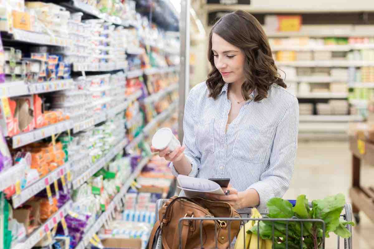 Donna al supermercato che controlla valori nutrizionali di un prodotto