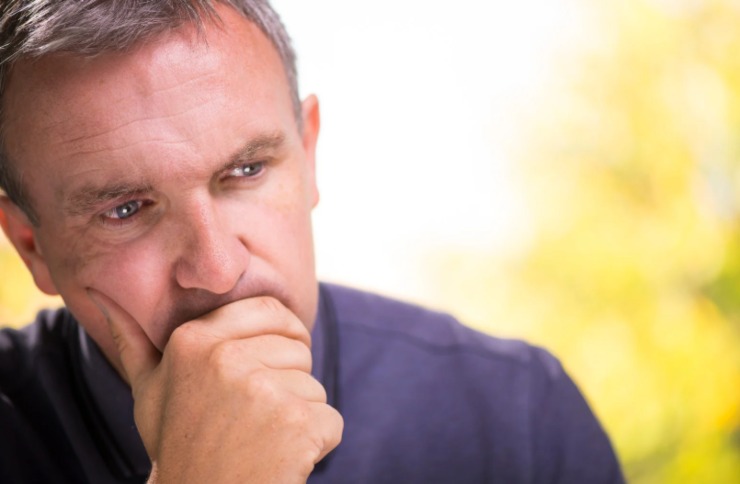 uomo preoccupato con una mano davanti alla bocca