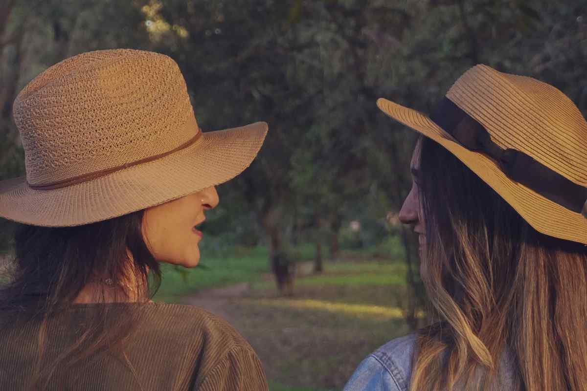 Due ragazze con un cappello di paglia che si guardano in un bosco