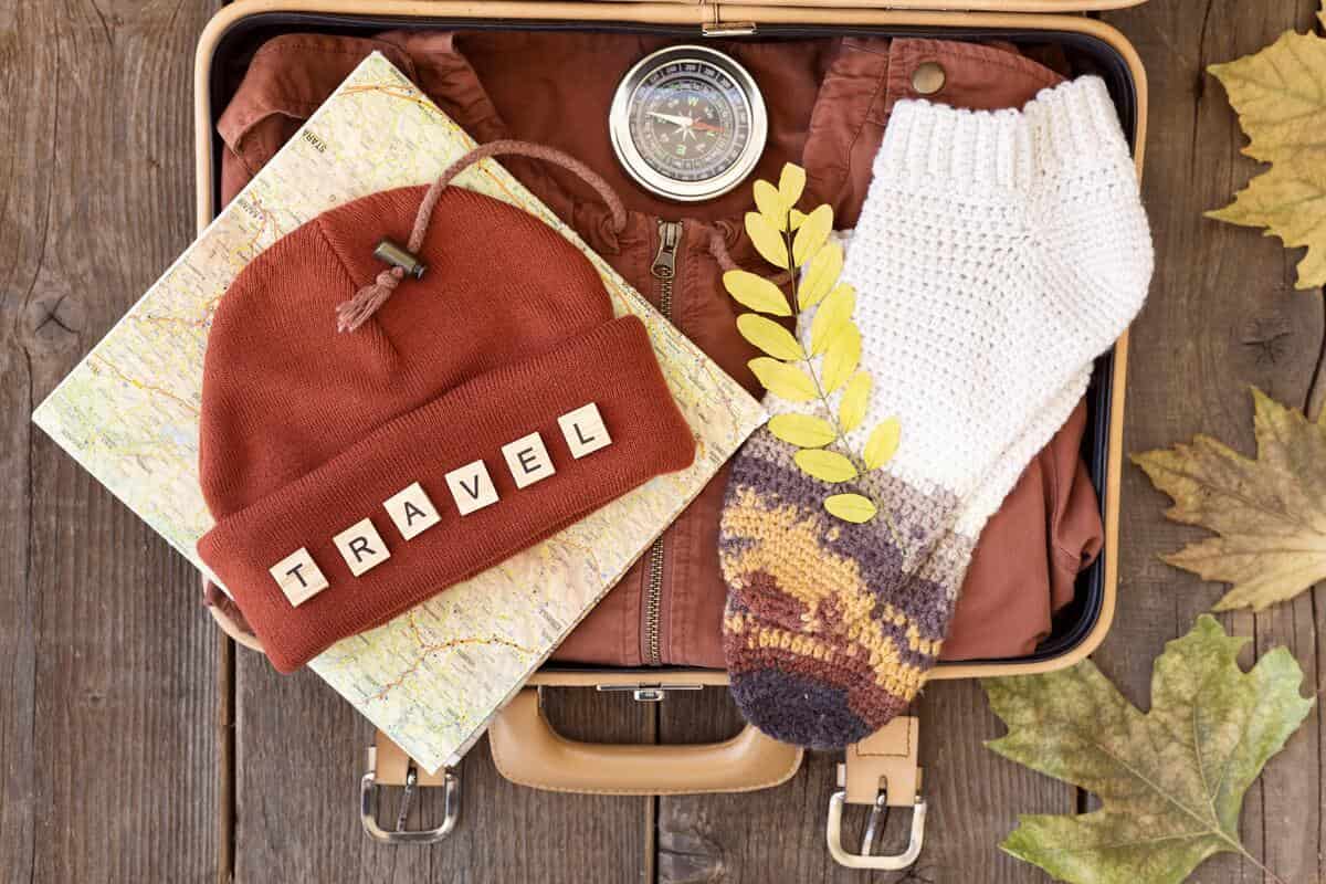 Valigia aperta con bussola, calze e berretto di lana 