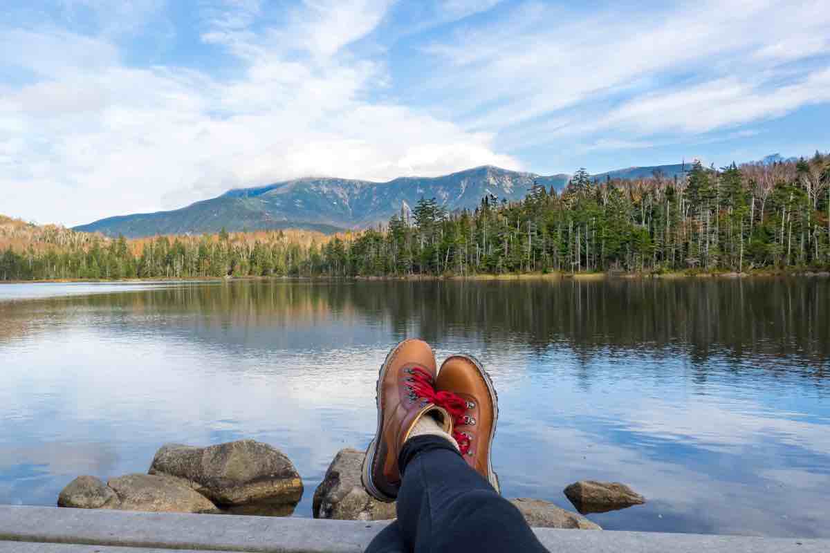 Persona distesa di fronte a lago di montagna