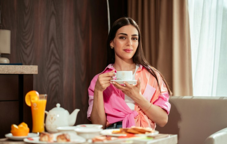 donna che fa colazione in hotel con in mano una tazza