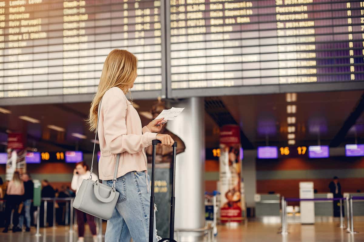 Ragazza in aeroporto davanti al tabellone dei voli