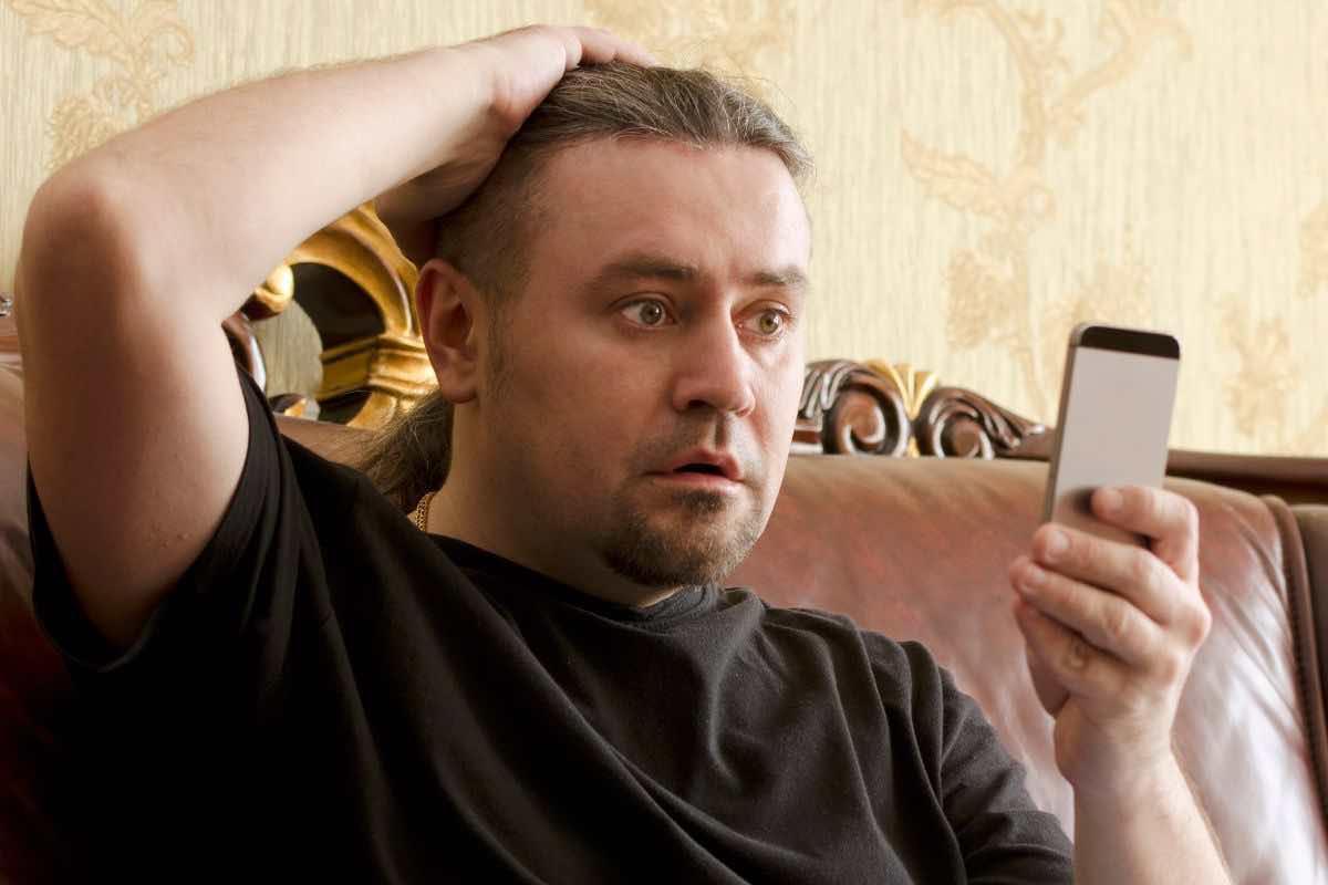 Uomo che guarda preoccupato il telefono